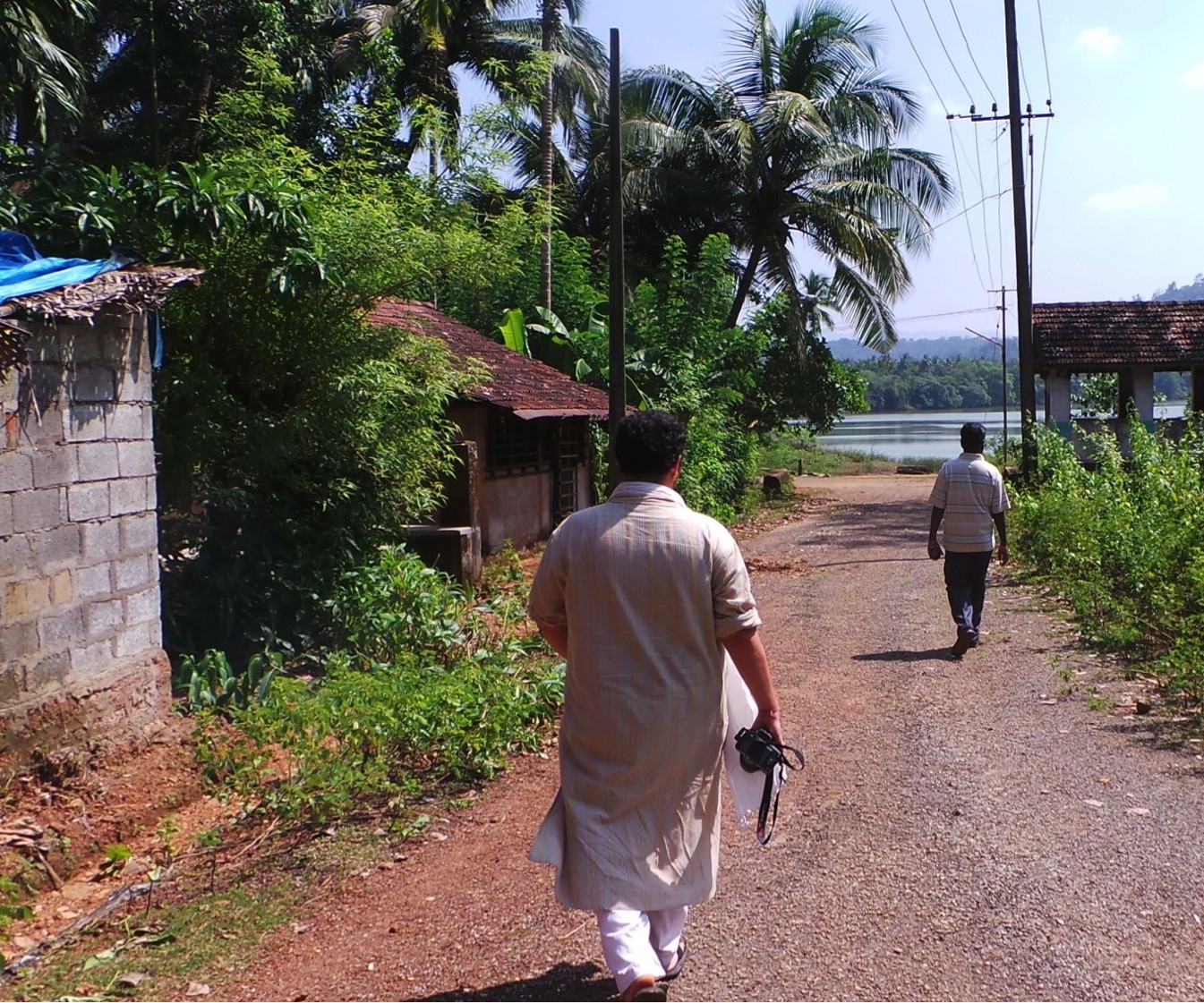 Two members of Panchabhuta's research team walking into Kagal village toward the Aghanashini Estuary, camera in hand